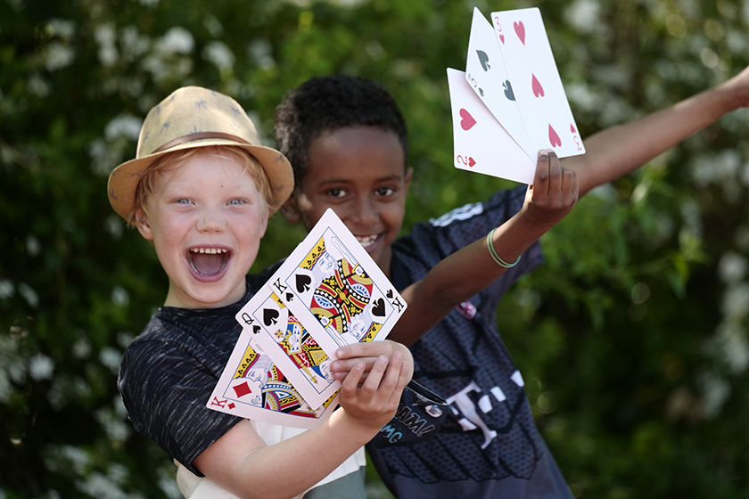 Zwei Kinder lachen und zeigen große Spielkarte.