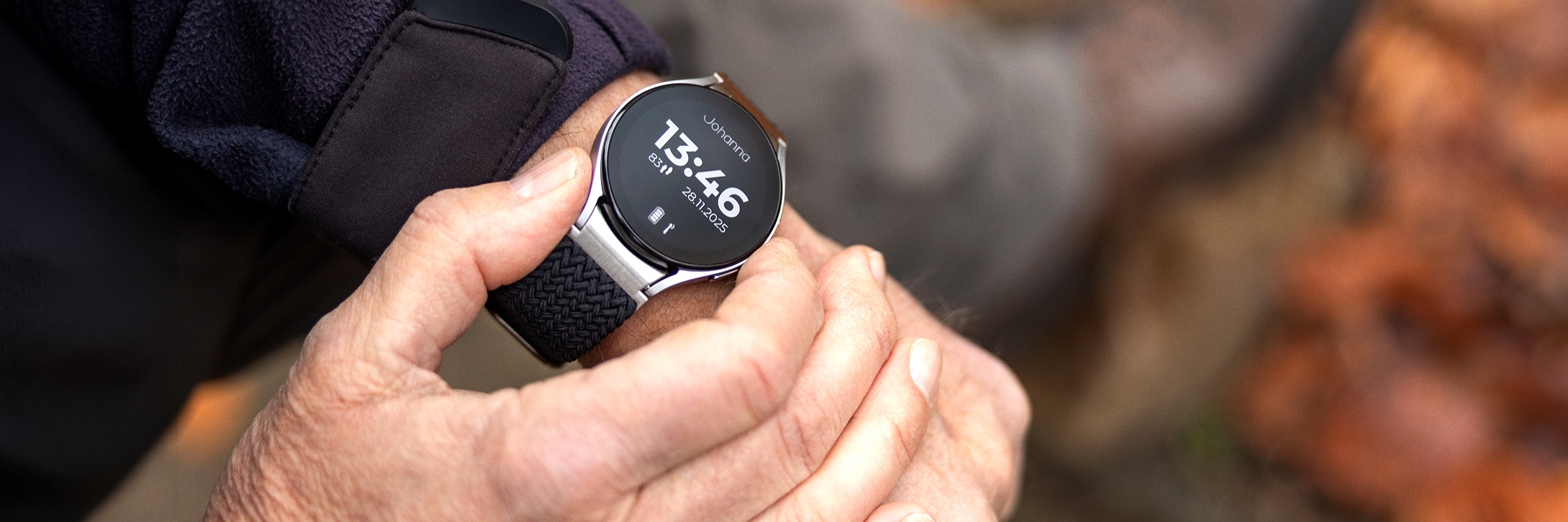 Nahaufnahme von Händen, die an einer Smartwatch durch Tastendruck einen Notruf auslösen.