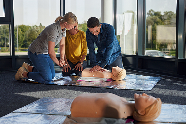 Der Kursleiter erklärt zwei Damen wie die Herz-Lungen Massage funktioniert