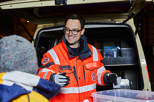 Ein ehrenamtlicher Helfer der Johanniter Bremen im Gespräch mit einem obdachlosen Menschen.
