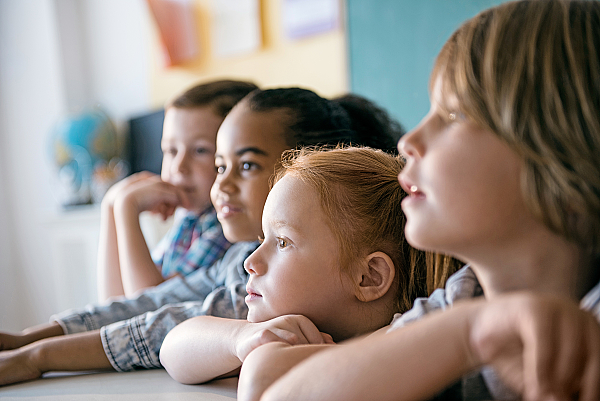 Schülerinnen und Schüler hören im Klassenraum zu.