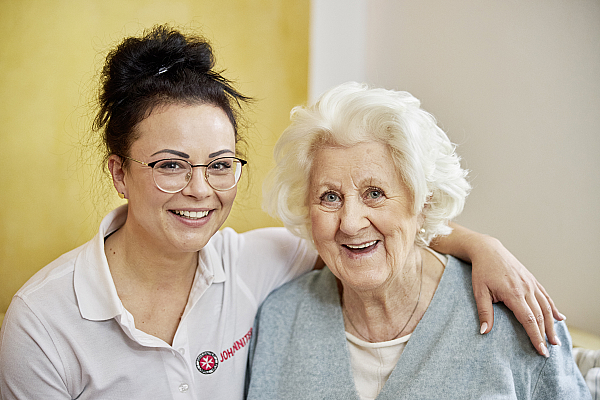 Mitarbeiterin Pflegedienst und Seniorin lächeln 