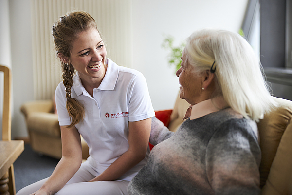 Auszubildende in der Pflege mit einer Kundin im Gespräch
