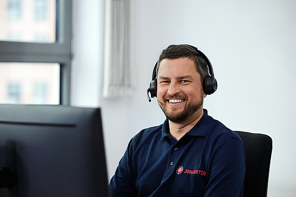 Arbeit beim Hausnotruf im Büro, Mann sitzt mit Headset am Schreibtisch
