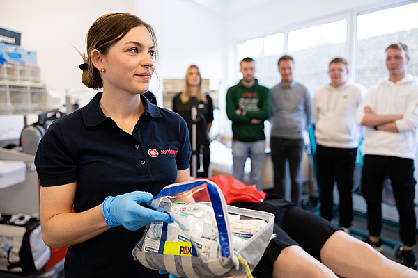 Erste-Hilfe-Ausbilderin beim Kurs, sie zeigt den Inhalt eines Erste-Hilfe-Koffers den Kursteilnehmern