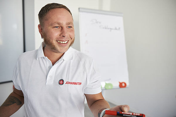 Ausbilder bei einem Erste-Hilfe-Kurs vor einem Whiteboard