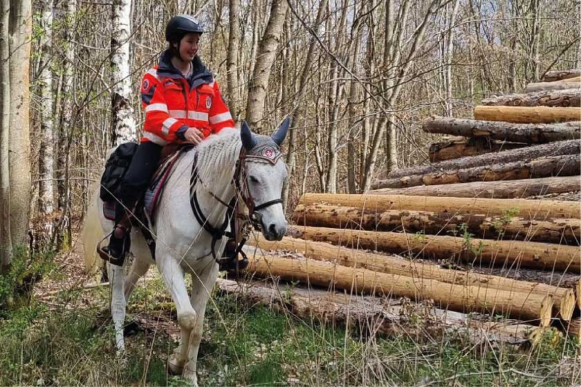 Eine Einsatzkraft der Johanniter-Reiterstaffel reitet durch den Wald im Rheingau-Taunus-Kreis.