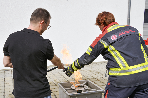 zwei Brandschutzhelfende in Rückansicht beim Löschen