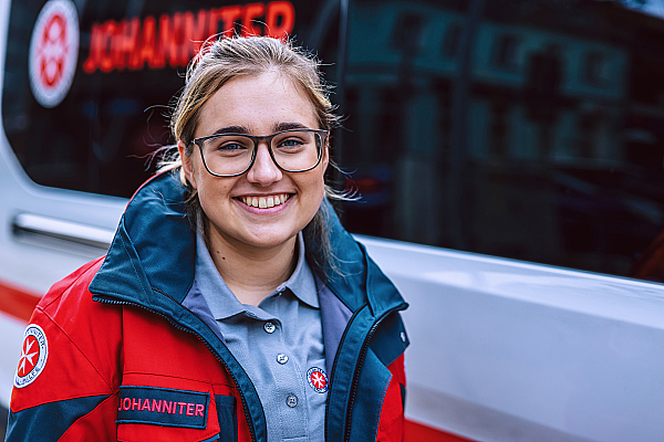 Eine junge Mitarbeiterin des Johanniter-Fahrdienst lächelt in die Kamera