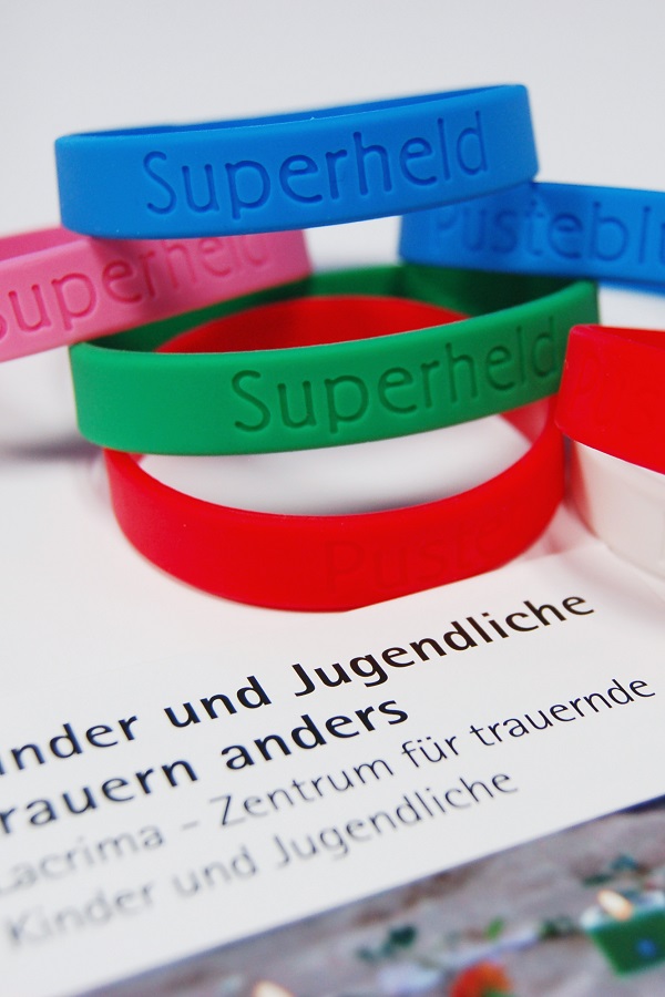 Trauerbänder mit den Aufschriften „Superheld“ oder „Pusteblume“ zum Gedenken an die Verstorbenen und zum Mut machen, innen ist die kleine, aber doch so wichtige Botschaft „ich bin bei dir“ verborgen.