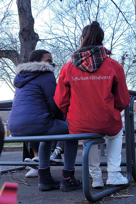 Schulsanitäter sitzen auf einer Bank.