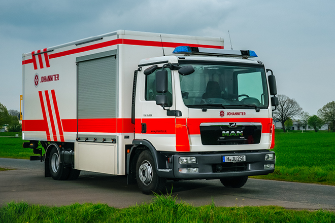 Ein rettungswagen steht auf einer Straße, im Hintergrund sind Bäume