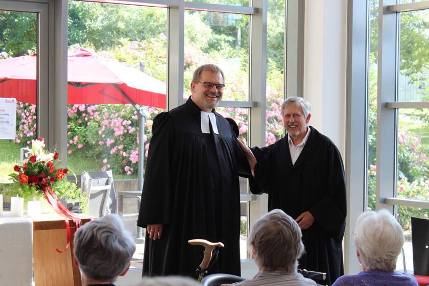 Pastor und Diakon stehen vorne, das Publikum hört gespannt zu. 