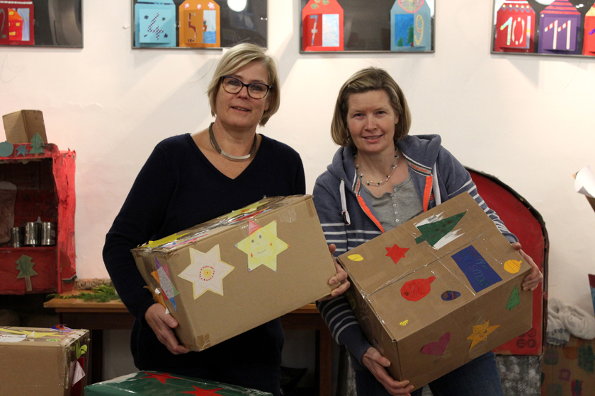 Lehrerin und Schulleiterin zeigen zwei der schön dekorierten Pakete. 