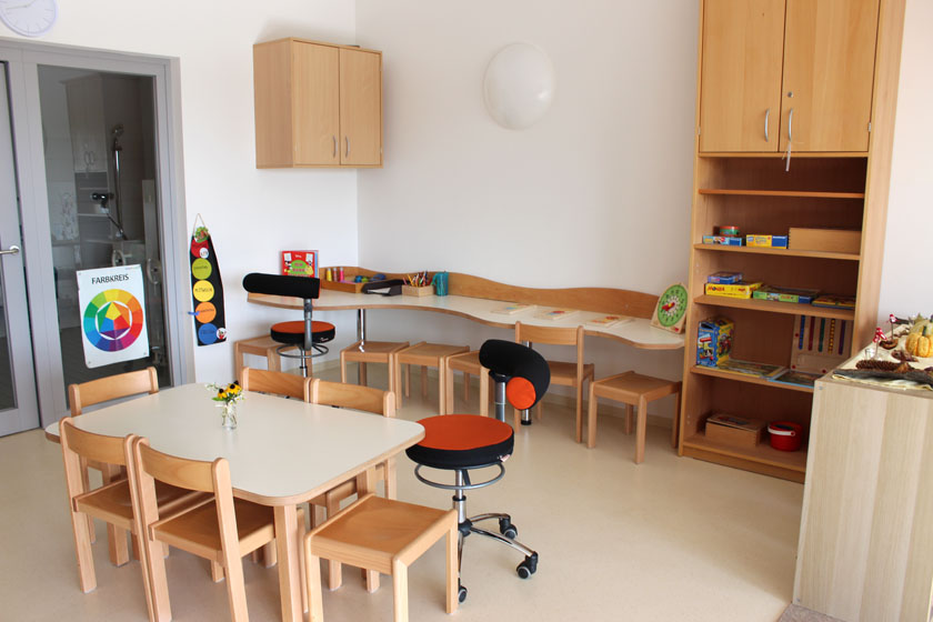 Spielsachen, kleiner Tisch mit Stühlen und Regal.