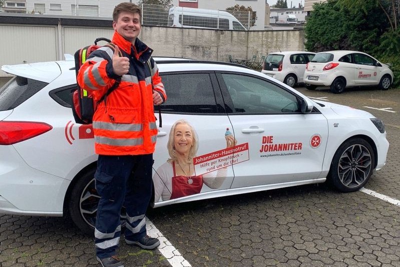 Matthias Pauls steht mit Notfallrucksack am Auto und hält den Daumen hoch