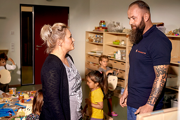 Ein Erzieher unterhält sich mit einer Kollegin in einer Kita.