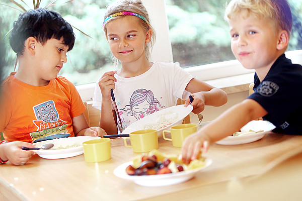 Drei Kinder beim gemeinsamen Essen.