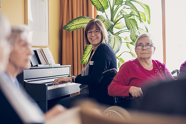 Bewohnerinnen lauschen einer Klavierspielerin