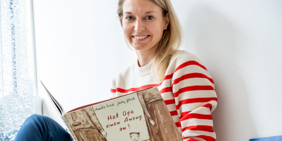 Lacrima-Teamleitung Svenja von Weitershausen blickt in die Kamera und hält ein Kinderbuch zum Thema Trauer in den Händen.