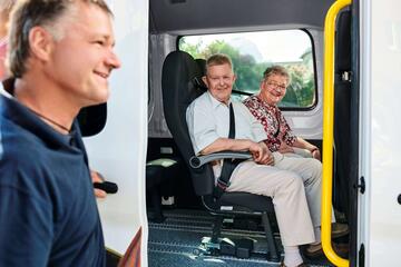 ein Mitarbeiter vom Fahrdienst bringt zwei Gäste zur Tagespflege
