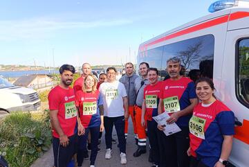 Neun Johanniter aus der Landesunterkunft Kiel stehen neben einem Johanniter Einsatzfahrzeug, sie tragen Sportkleidung