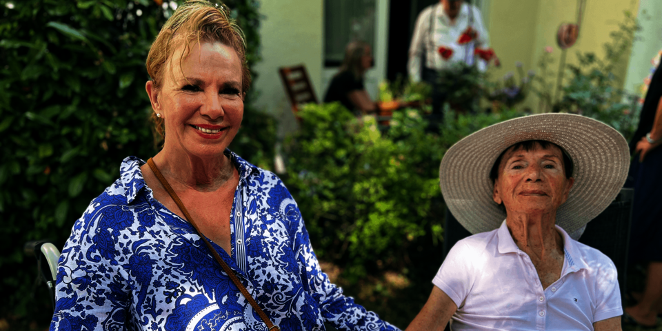 eine ältere und eine jüngere Frau sitzen gemeinsam im Garten