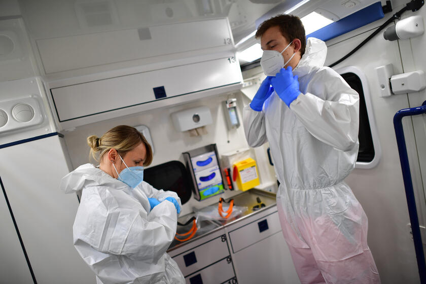 Mitarbeitende des Johanniter-Rettungsdienst legen sich Corona-Schutzkleidung an.