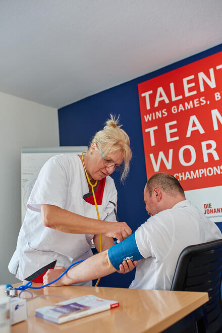 Eine Mitarbeiterin misst Blutdruck