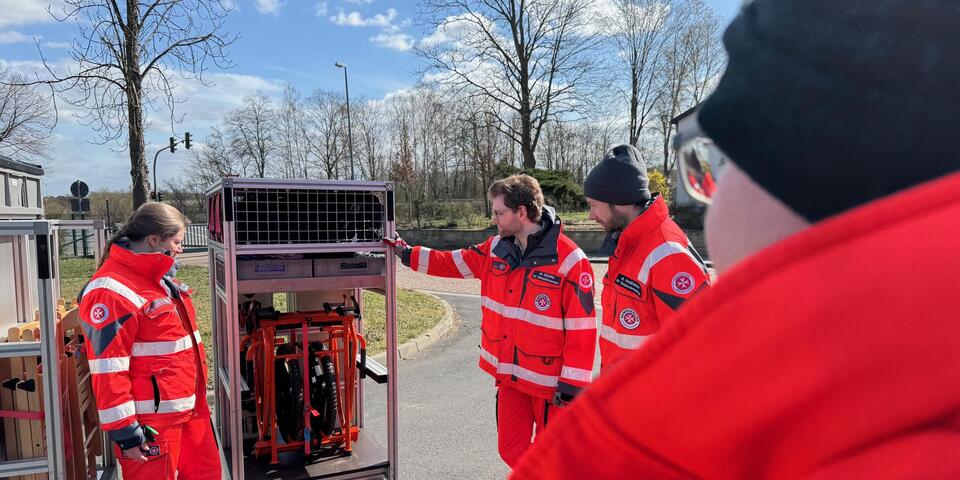 Johanniter schauen sich elektrische Geräte in einem Rollwagen an