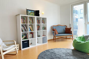 Ein Raum mit gemütlichen Sesseln und einem Bücherregal voller Bücher.