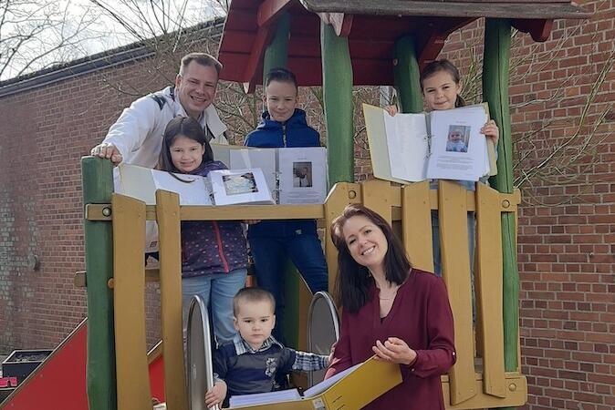 Familie Lies im stehen und sitzen im und am Kinderspielhaus