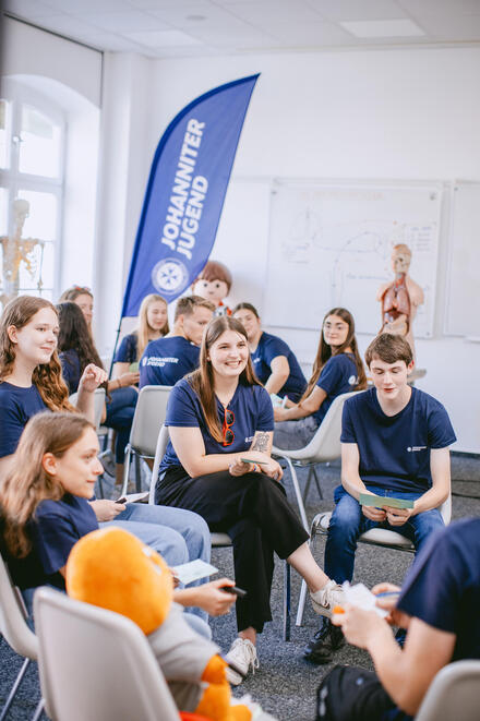 Jugendliche der Johanniter-Jugend sitzen in einem Stuhlkreis und beteiligen sich angeregt an einer Diskussion.