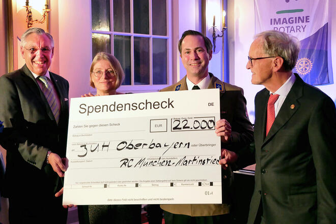 Mehrere Leute halten einen großen Spendencheck an die Johanniter Oberbayern.