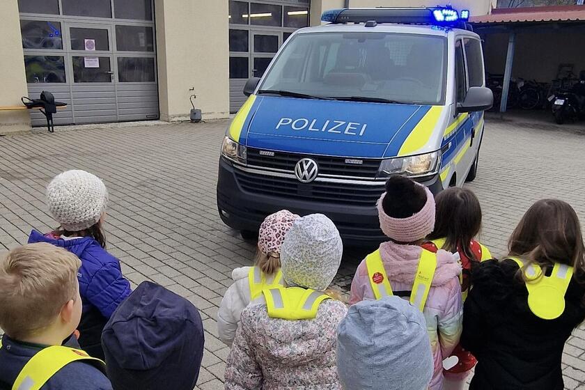 Kinder des Kinderhauses stehen vor einem Polizei Auto