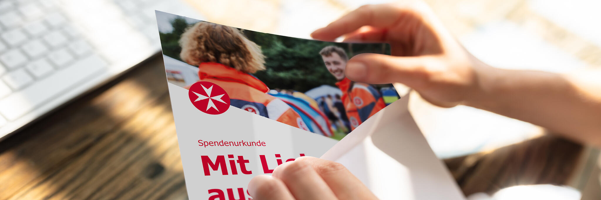 Zwei Hände ziehen eine Gutscheinkarte aus einem Briefumschlag