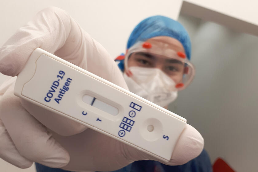 Ein Johanniter-Mitarbeiter in Schutzkleidung zeigt einen Corona-Schnelltest.