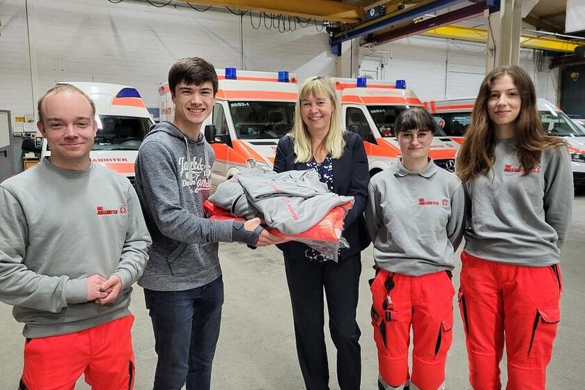 Felix Flügger von der JUG-San erhält von Sabine Fligg seine neue Einsatzkleidung. Ortsjugendleiter Patrick Glander (links) sowie Dena Bartz und Eske Albert (von rechts) freuen sich über die Unterstützung.