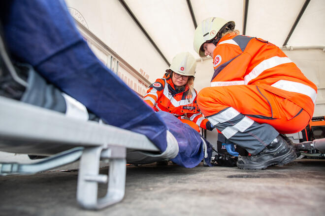 Zwei Helfende des Katastrophenschutzes helfen einer Person.