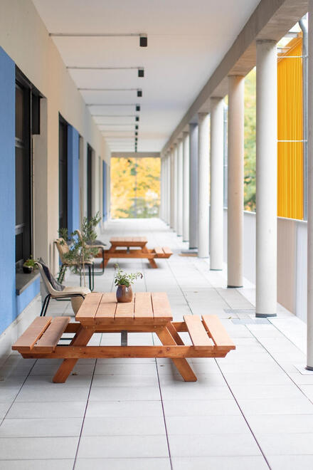 Anblick der Terasse der Kita Lumi Natura mit Holzbänken im Vordergrund.