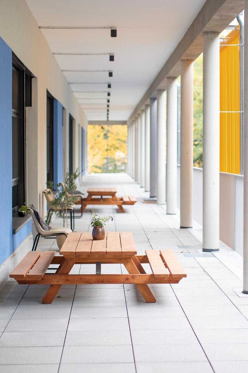 Anblick der Terasse der Kita Lumi Natura mit Holzbänken im Vordergrund.