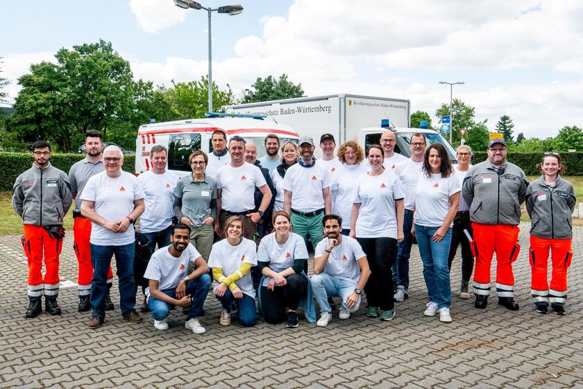 freiwillige Helfende Mitarbeitende von dem Sika Unternehmen und Ehrenamtliche Sanitäterinnen und Sanitäter der Johanniter Mannheim lächeln für ein Gruppenbild in die Kamera.