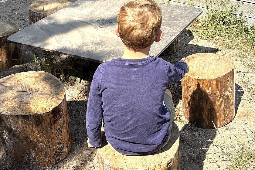 Kind sitzt auf Sitzbaustamm