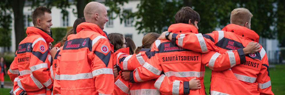 Gruppe Rettungssanitäter von hinten. Das Bild vermittelt ihre Motivation und den Zusammenhalt.