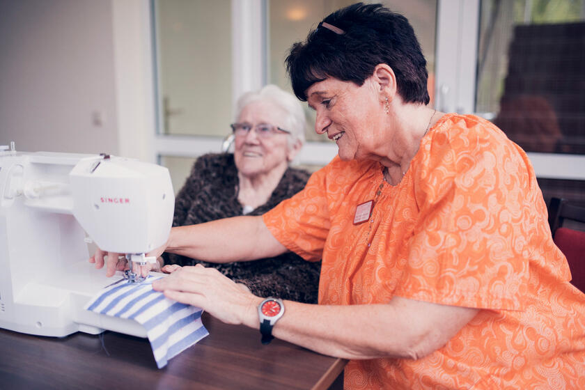 Betreuungskraft und Bewohnerin beim Nähen 