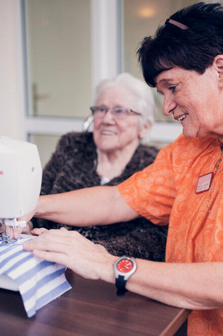 Betreuungskraft und Bewohnerin beim Nähen 