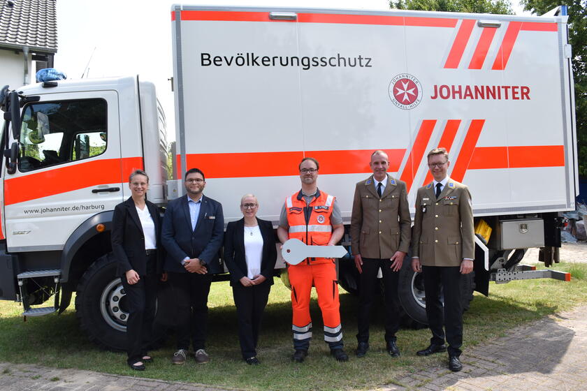 Mehrere Personen posieren als Gruppe vor einem LKW des Bevölkerungsschutzes