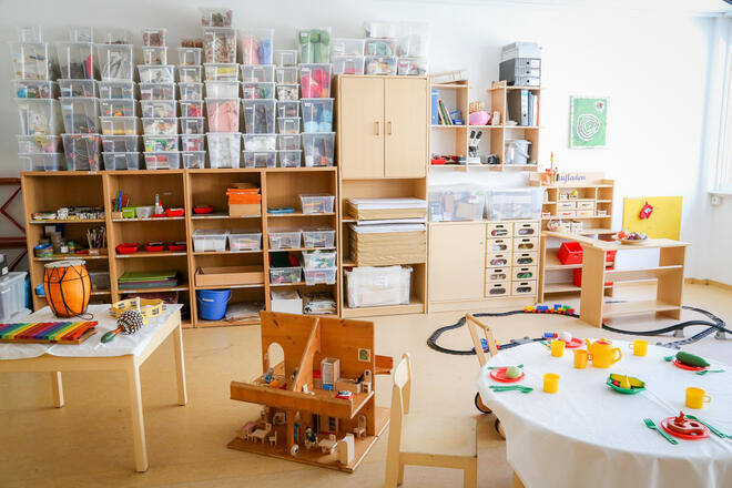 Kita-Alltag: Bastelregale, Spieltisch und kreative Materialien im Gruppenraum.