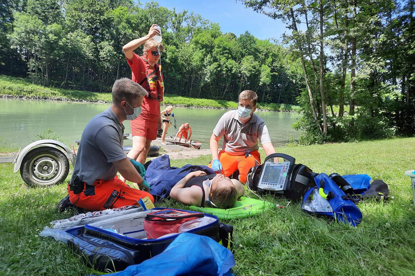 Nachgestellte Übung bei der eine Person auf der Wiese liegend medizinisch versorgt wird.