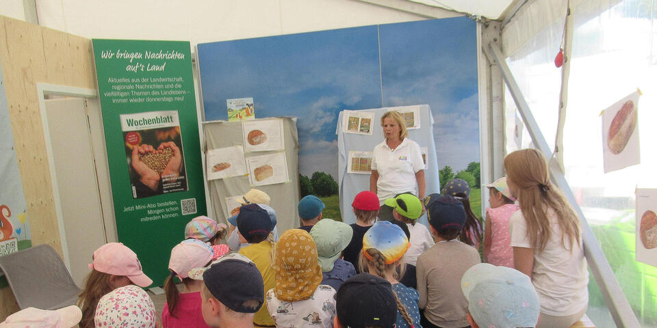 Eine Frau erklärt Kindern etwas in einem Pavillon